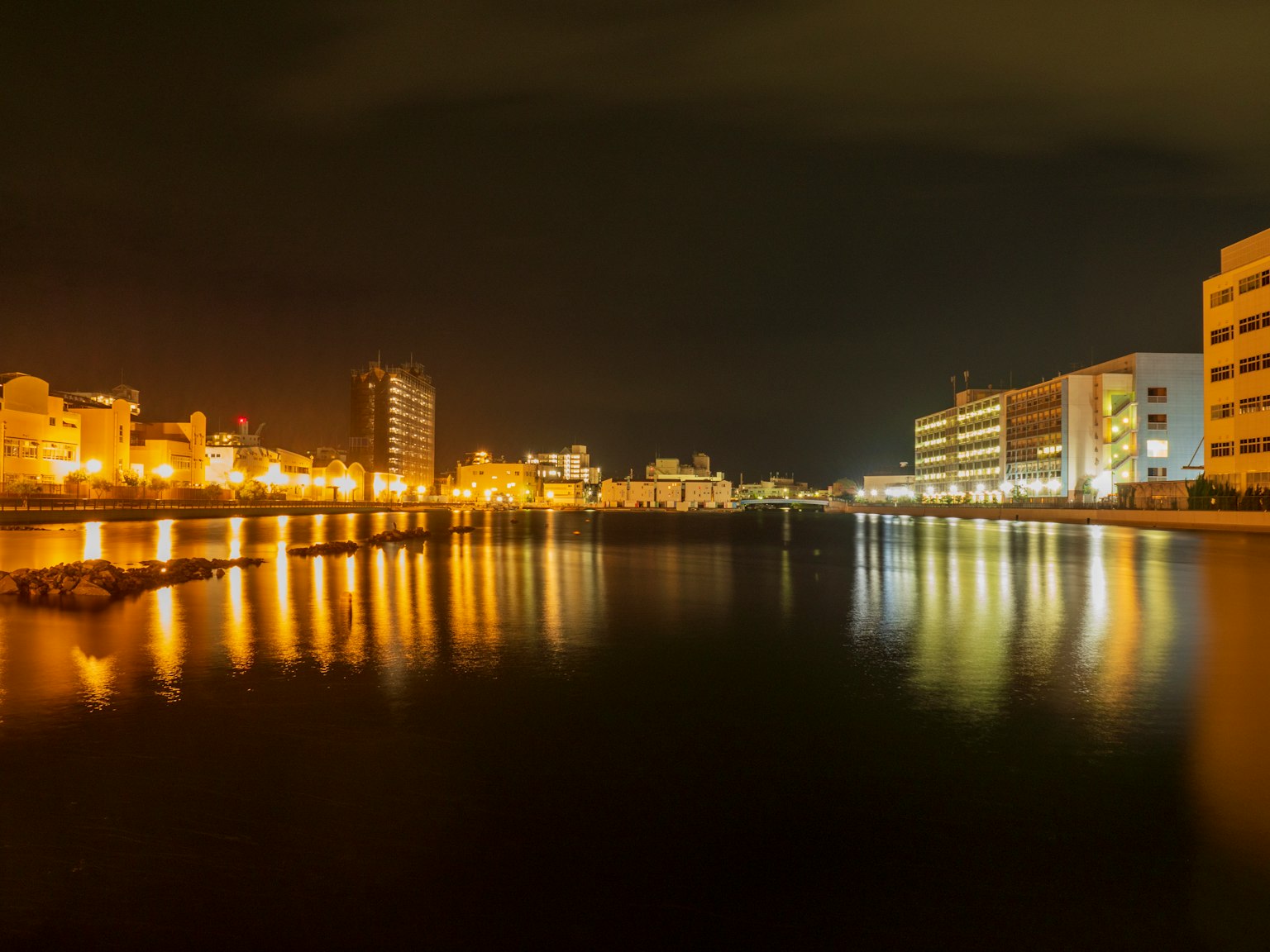 Night view of city buildings reflecting on the river