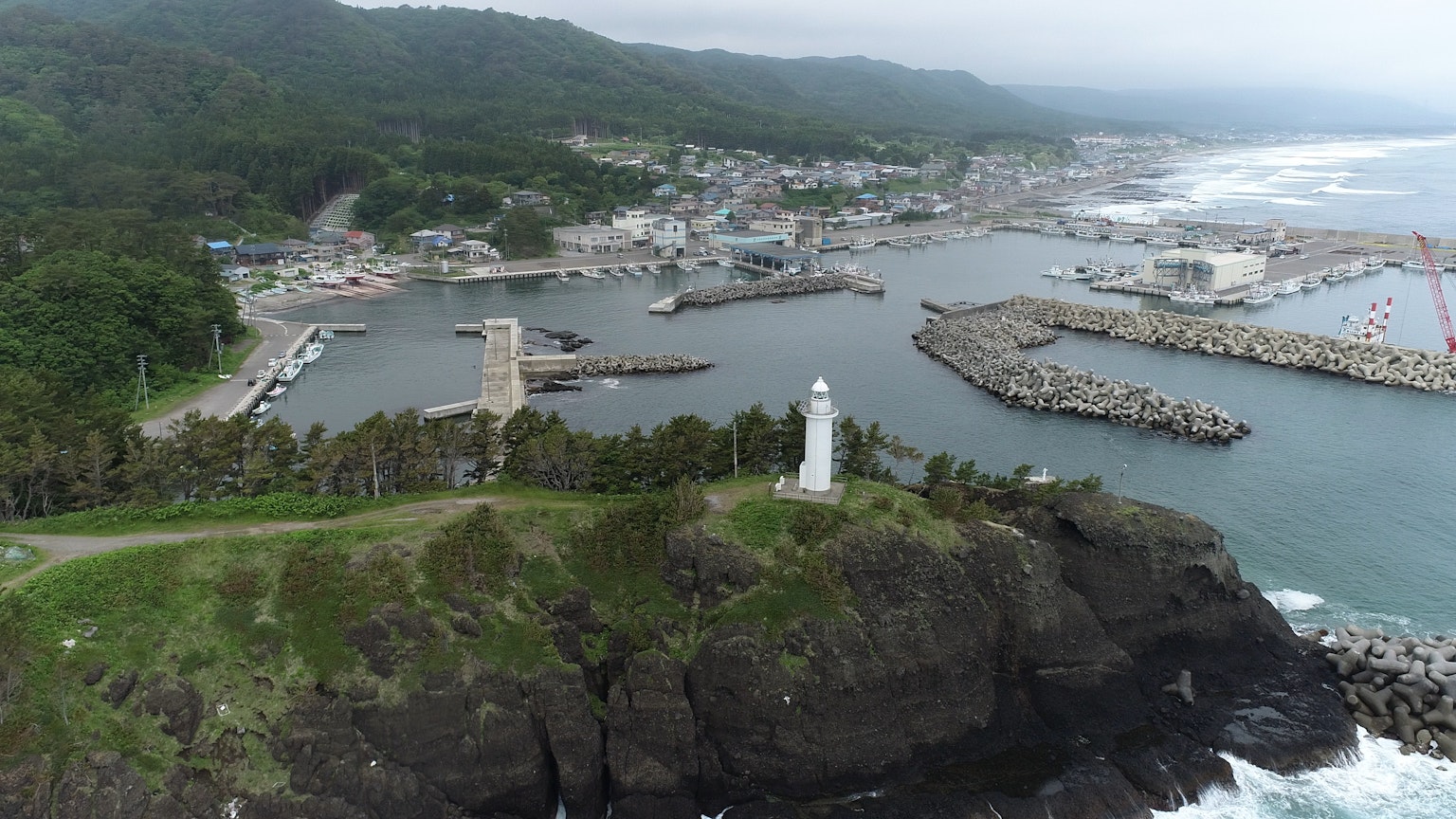 海岸風景，燈塔和港口被霧蒙蒙的山脈環繞