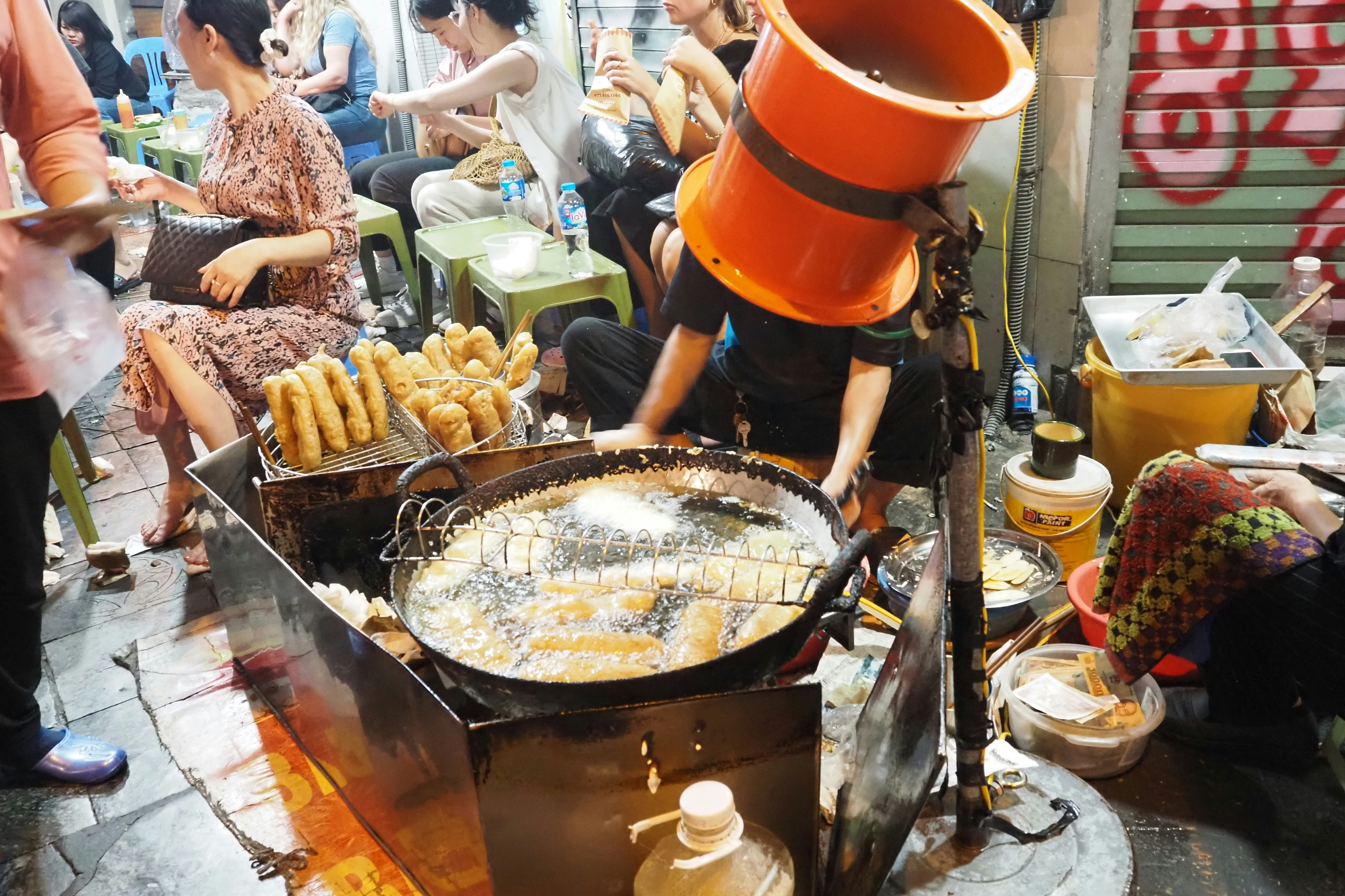 街頭小吃攤用大油鍋炸制小吃的場景