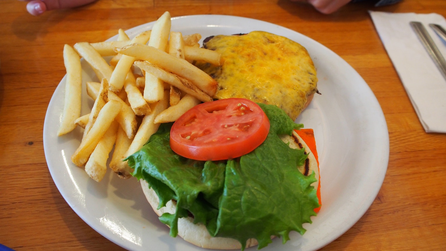 A plate with a sandwich featuring lettuce and tomato alongside French fries