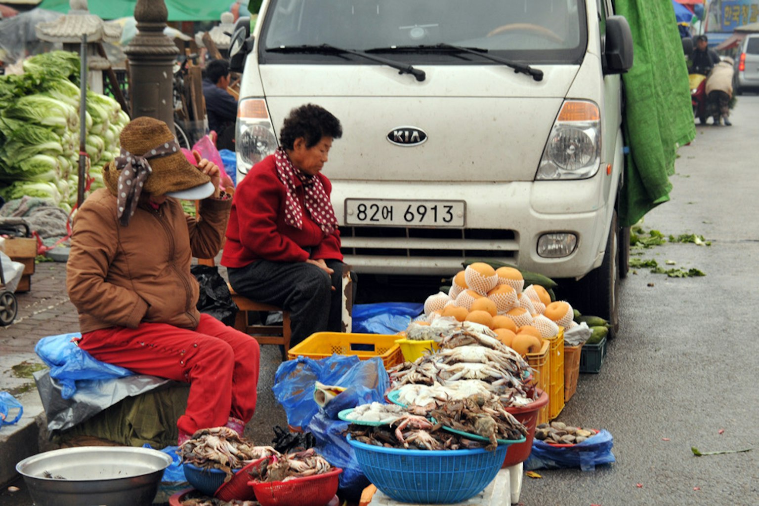 Phụ nữ bán cá ở chợ với một chiếc xe trắng