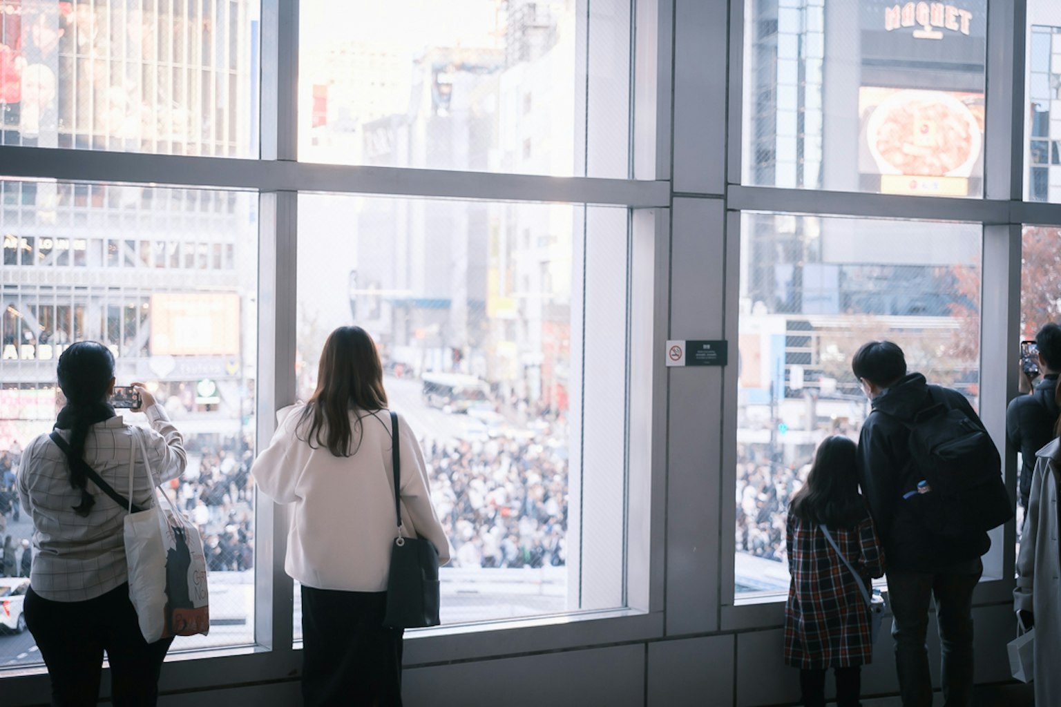 Personas mirando por la ventana a la multitud en Shibuya Crossing