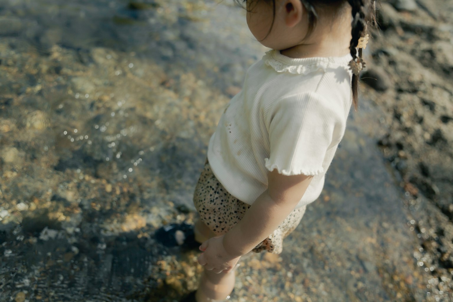 Bambino in piedi nell'acqua bassa sulla spiaggia