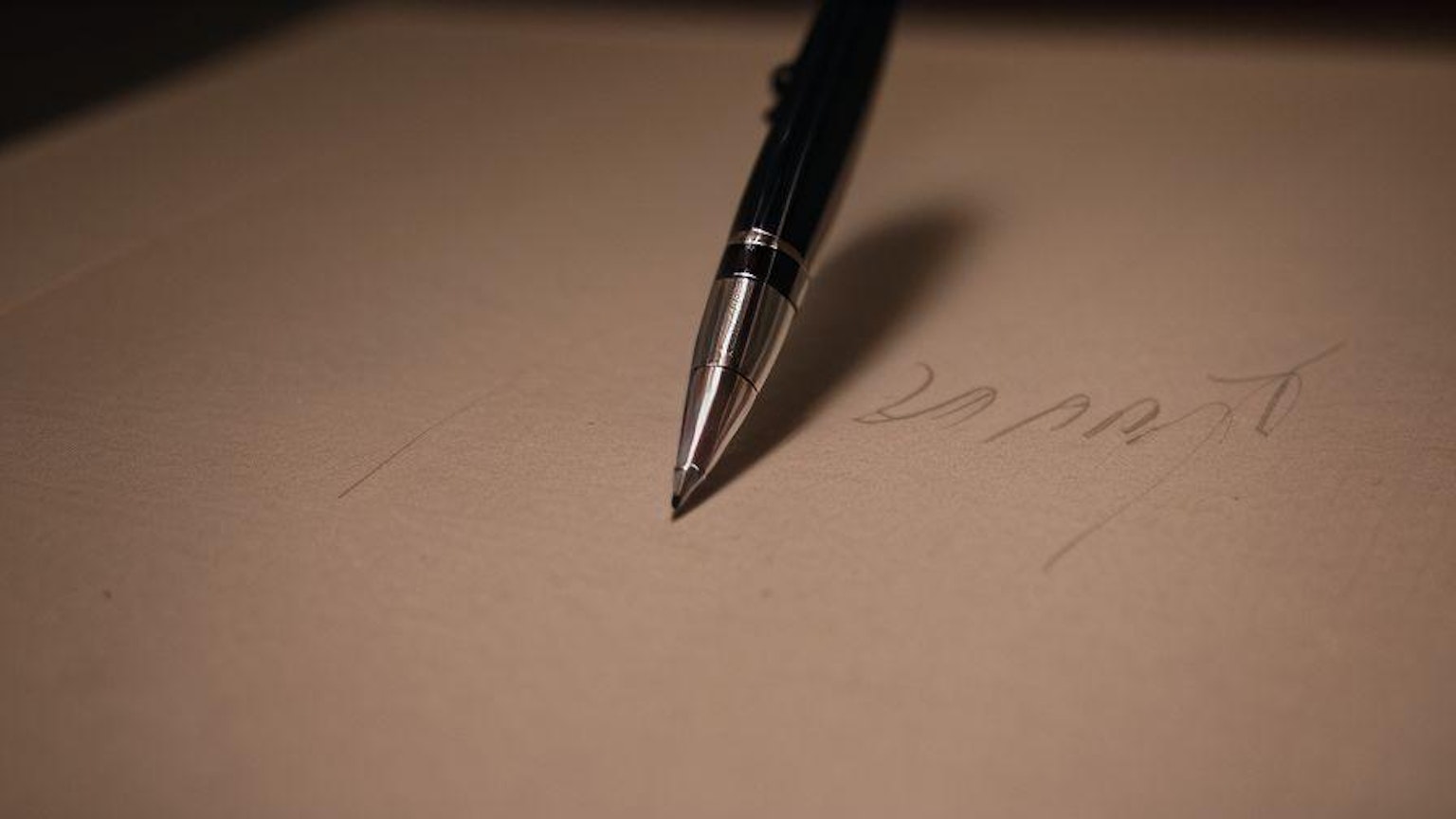 Sebuah pena terletak di atas selembar kertas kosong