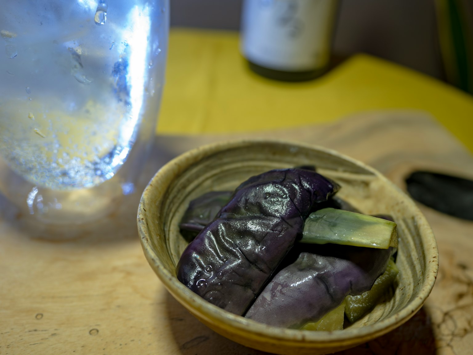 Ciotola di melanzane viola con un bicchiere d'acqua sullo sfondo
