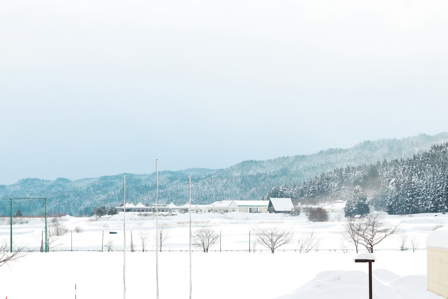 Schneebedeckte Landschaft mit fernen Bergen und einer kleinen Hütte
