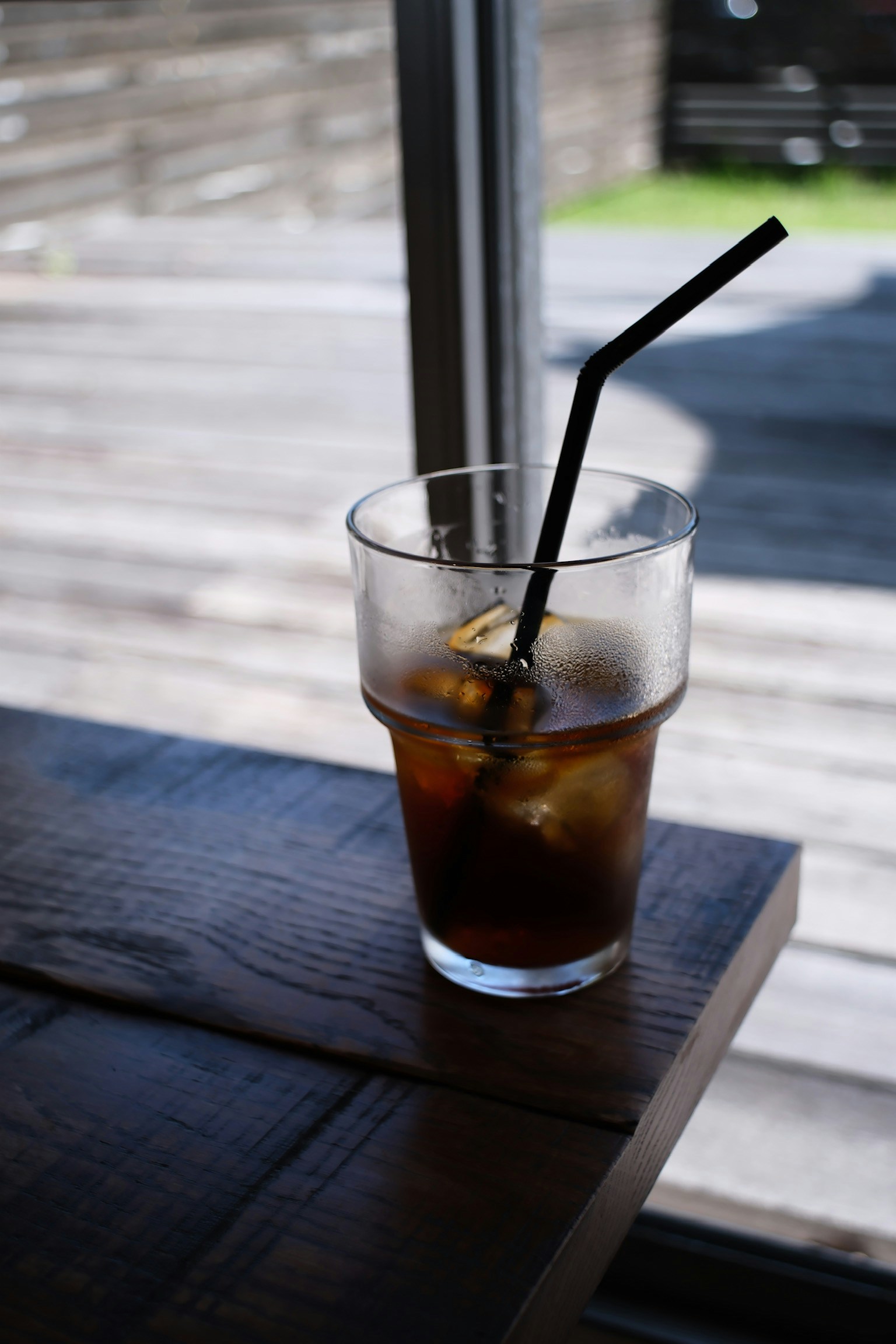 Gelas kopi es di atas meja kayu dengan sedotan