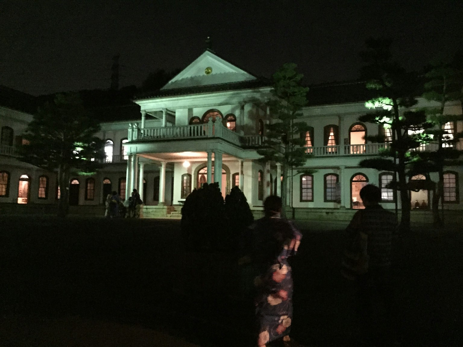 Klassische westliche Villa bei Nacht beleuchtet mit Menschen in traditioneller Kleidung
