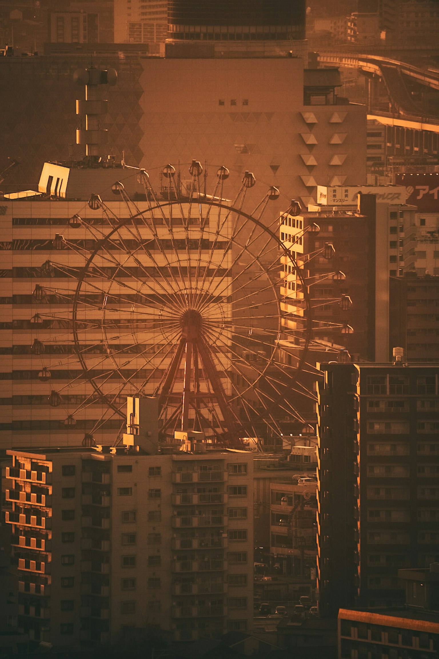 Riesenrad silhouettiert gegen einen Sonnenuntergang mit Stadtgebäuden