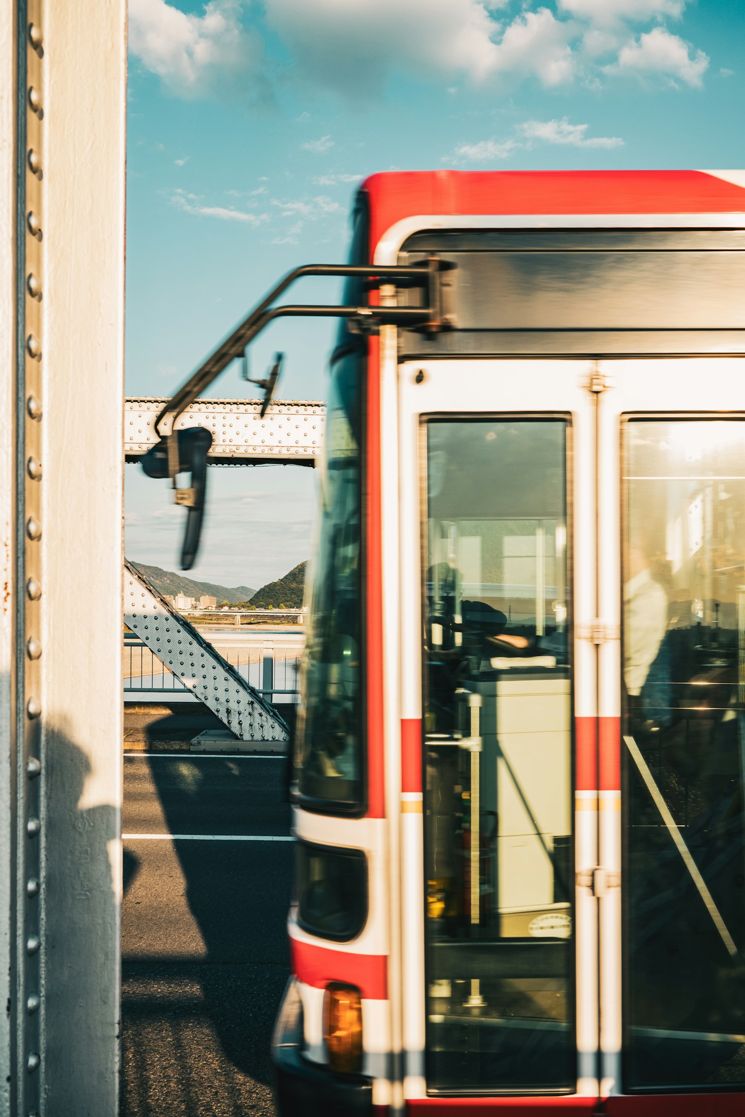 Red bus parked near a bridge with a scenic background