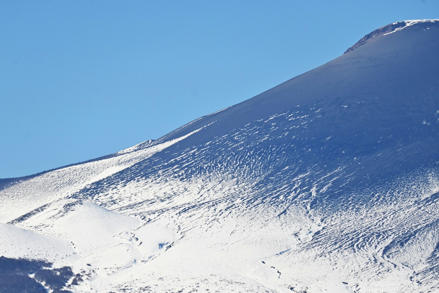 Pendiente de montaña cubierta de nieve con cielo azul claro