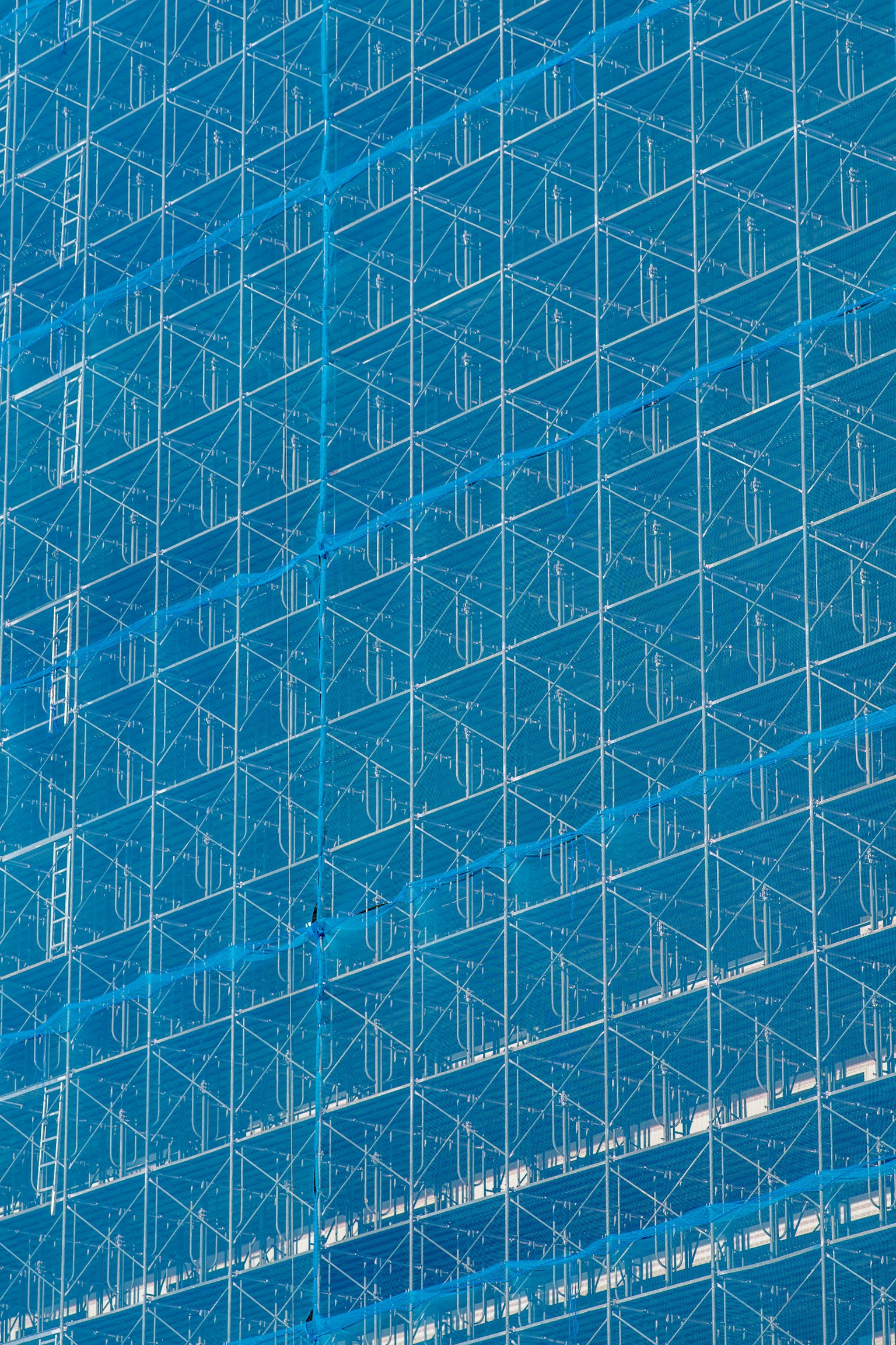 Geometrisches Gittermuster an der blauen Fassade eines Gebäudes