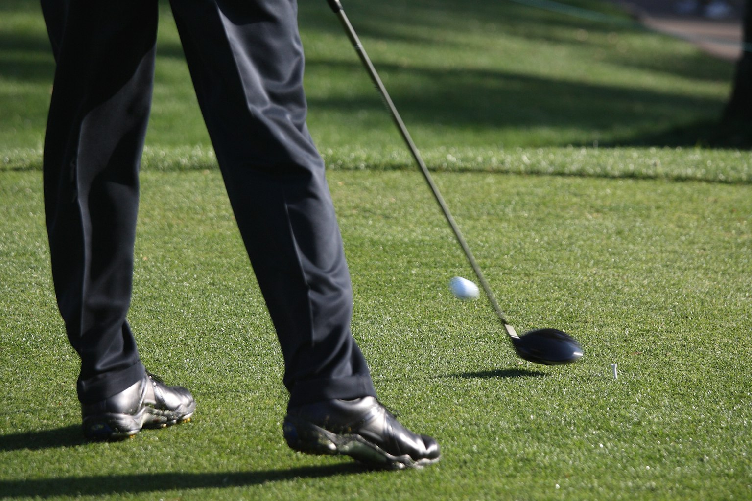 Gambe di un golfista con un bastone pronto a colpire una palla sul green