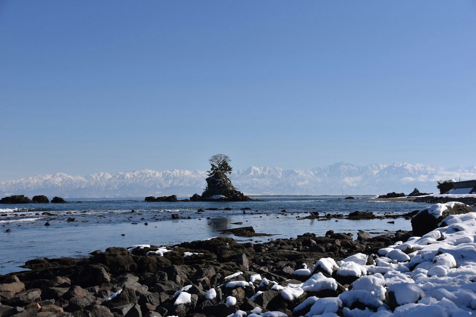 Scène océanique avec des rochers enneigés et une petite île
