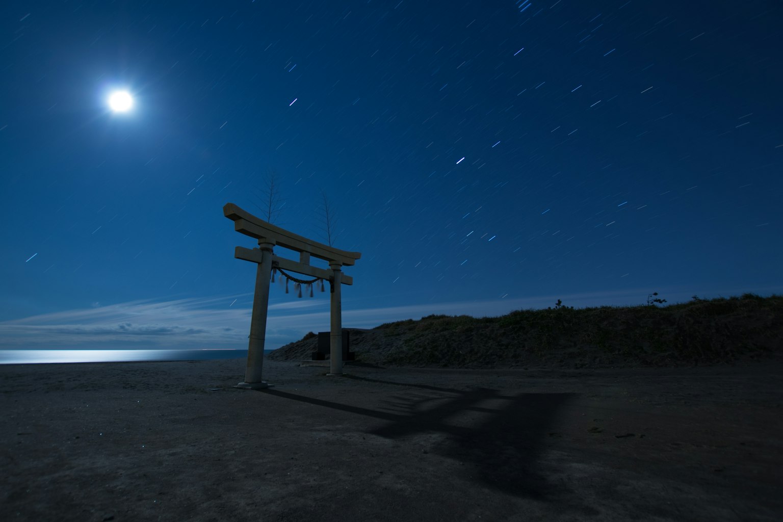 Torii iluminado por la luz de la luna bajo un cielo estrellado