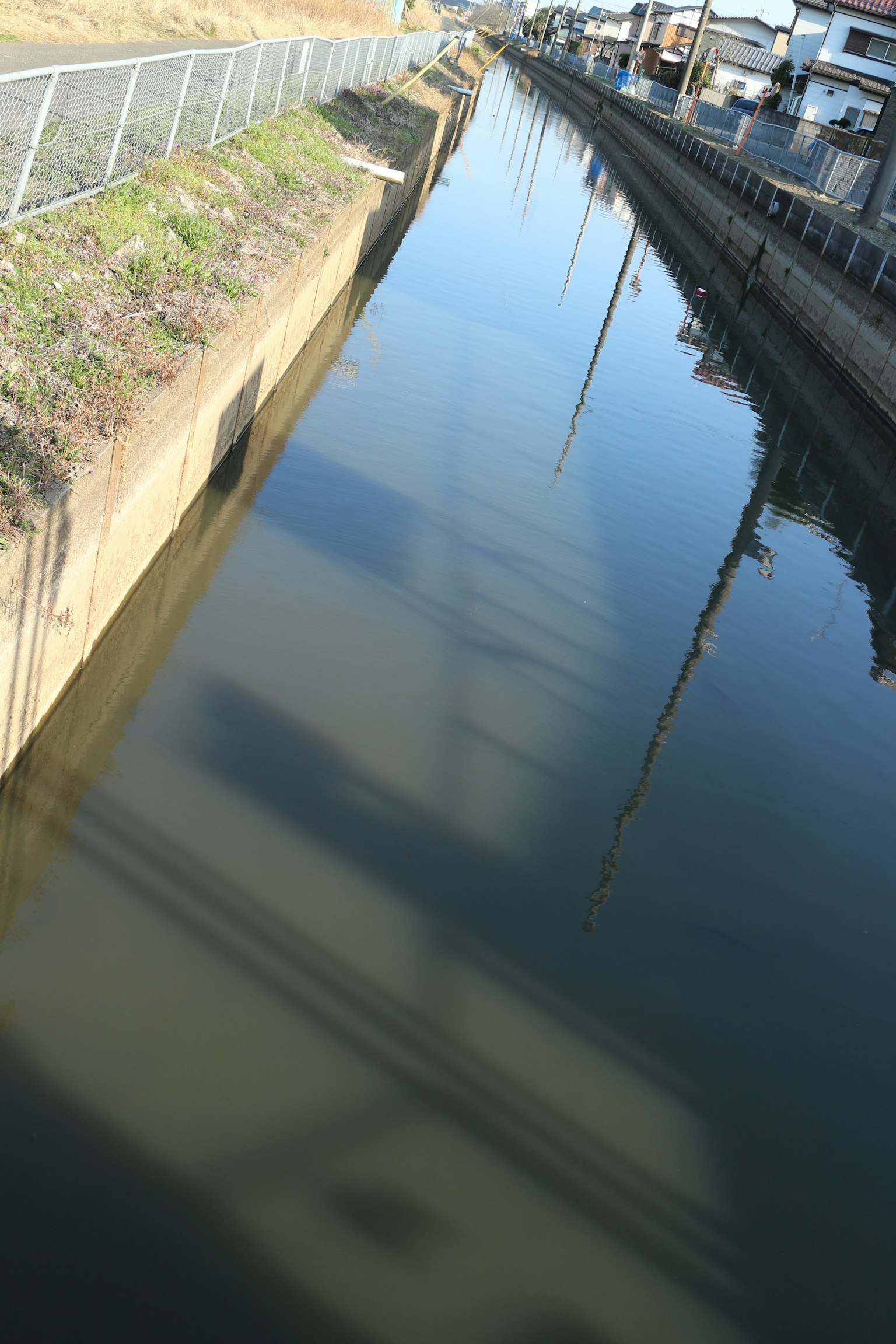 A view of a canal reflecting shadows and surrounding structures