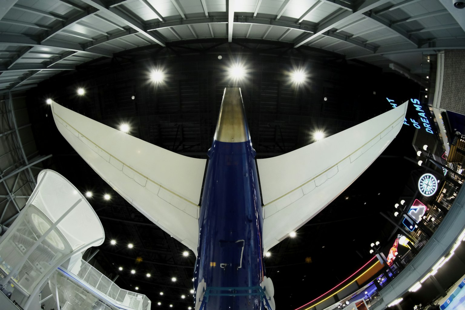 View from below a large airplane tail with bright ceiling lights