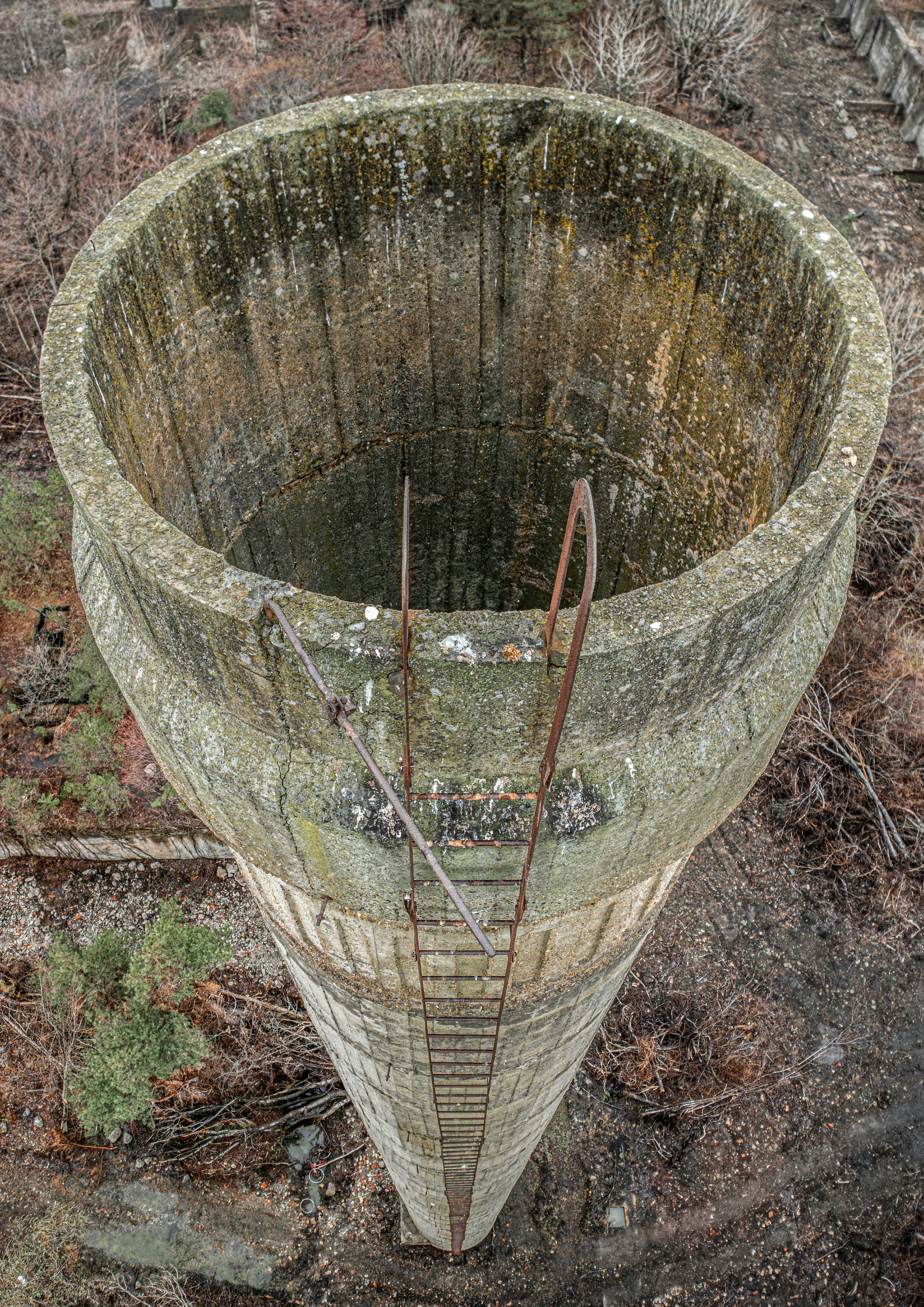 rusted funnel-shaped structure in an abandoned outdoor ruin