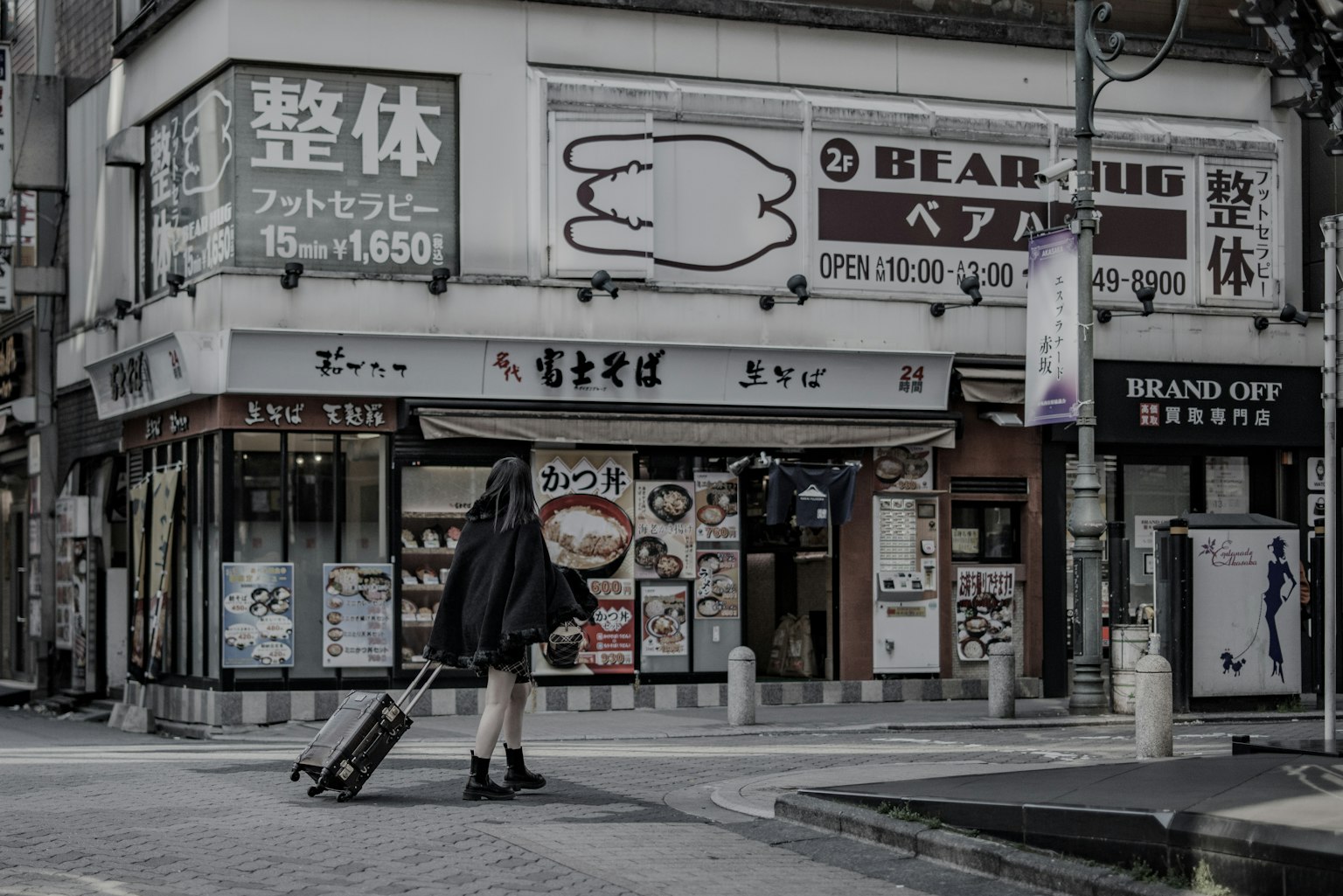 一个人站在街角商店前,手里提着行李
