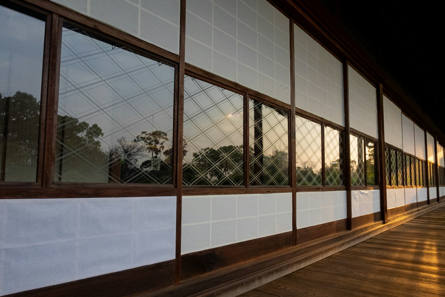 Holzaußenansicht eines japanischen Gebäudes mit Fenstern, die den Sonnenuntergang reflektieren