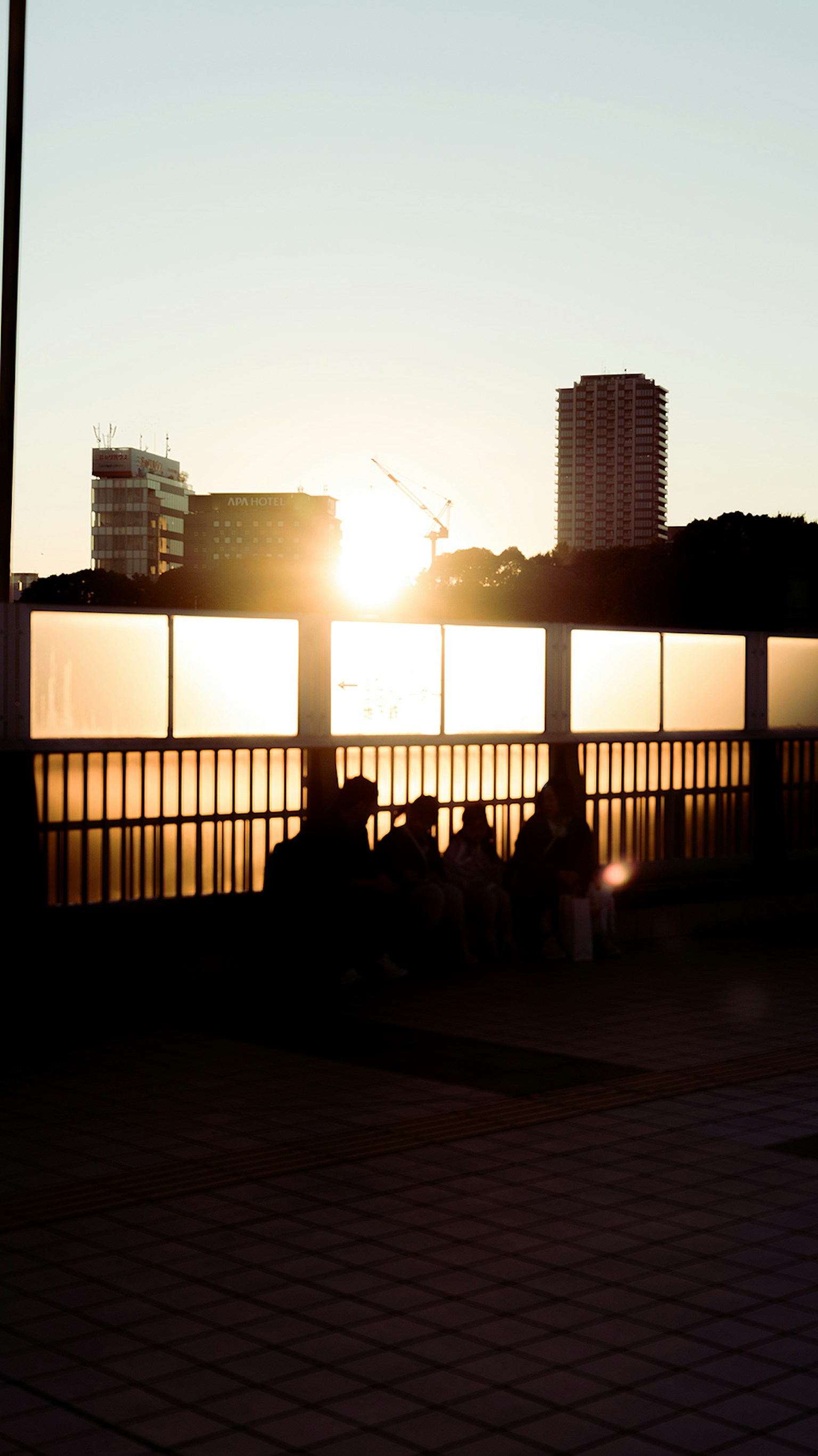 Silhouettes of people against a sunset with urban buildings