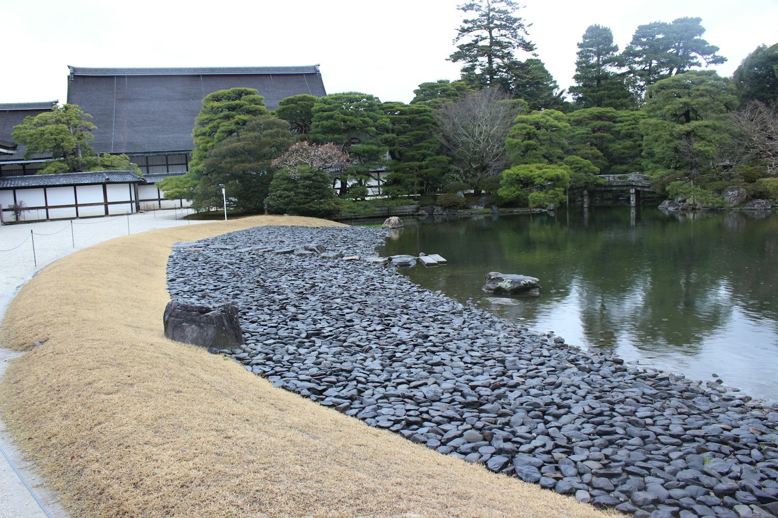 Scène de jardin japonais serein avec une rive en pierre et une surface d'eau calme