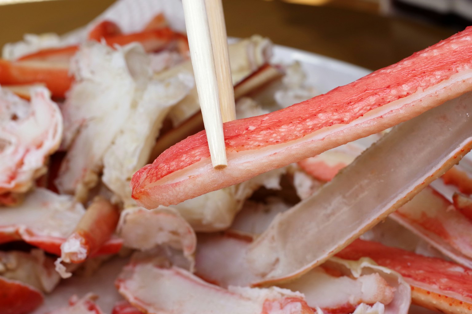 筷子夹起蟹肉，背景是丢弃的蟹壳