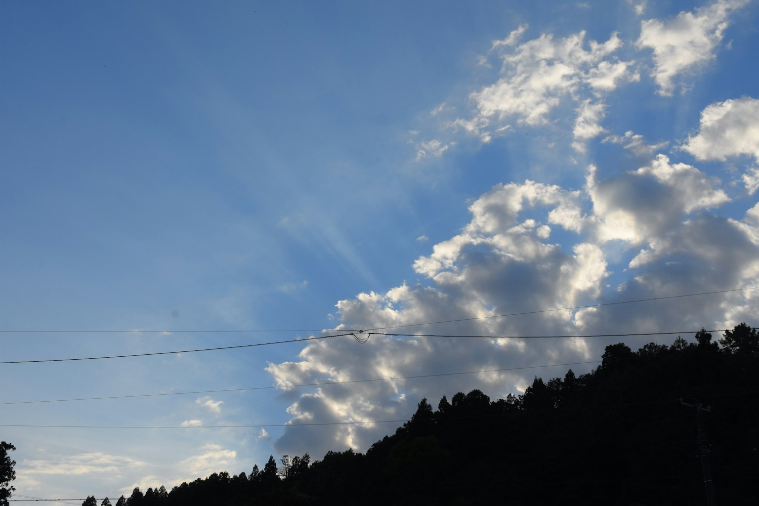 Ciel bleu lumineux avec des nuages blancs et des montagnes lointaines visibles