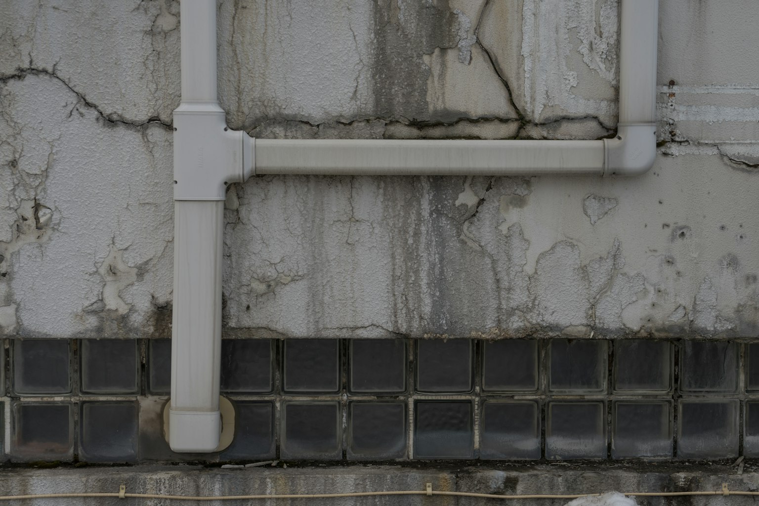 Partie d'un bâtiment avec des tuyaux blancs et une texture de mur fissuré
