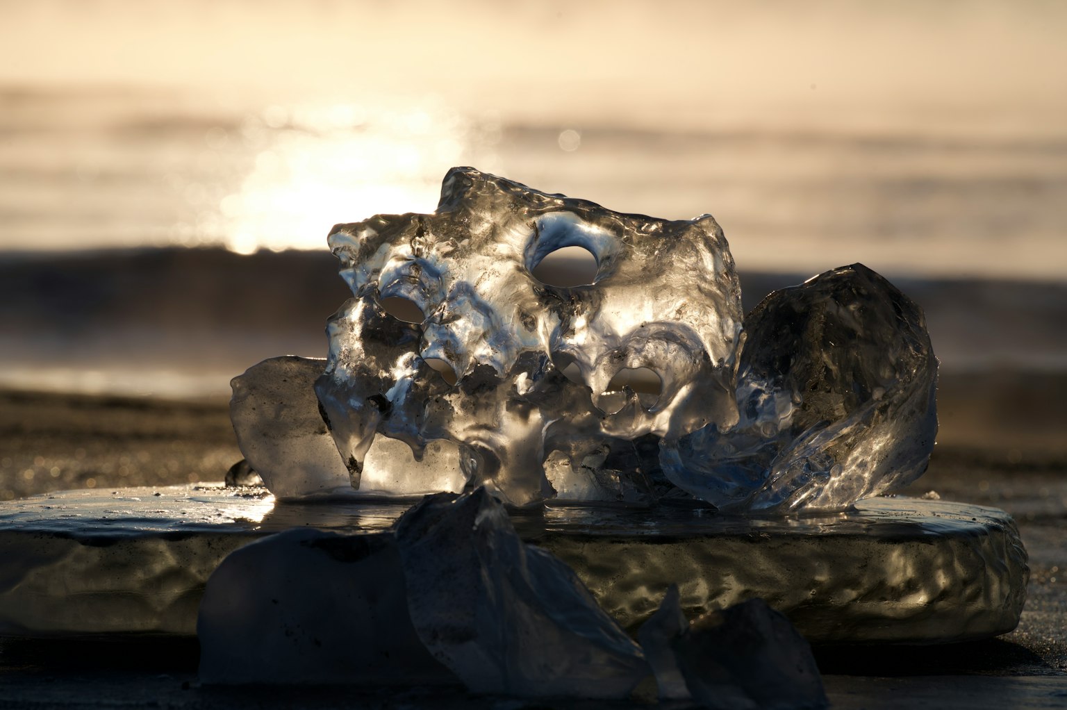 Ein transparenter Eisblock am Strand, der den Sonnenuntergang reflektiert