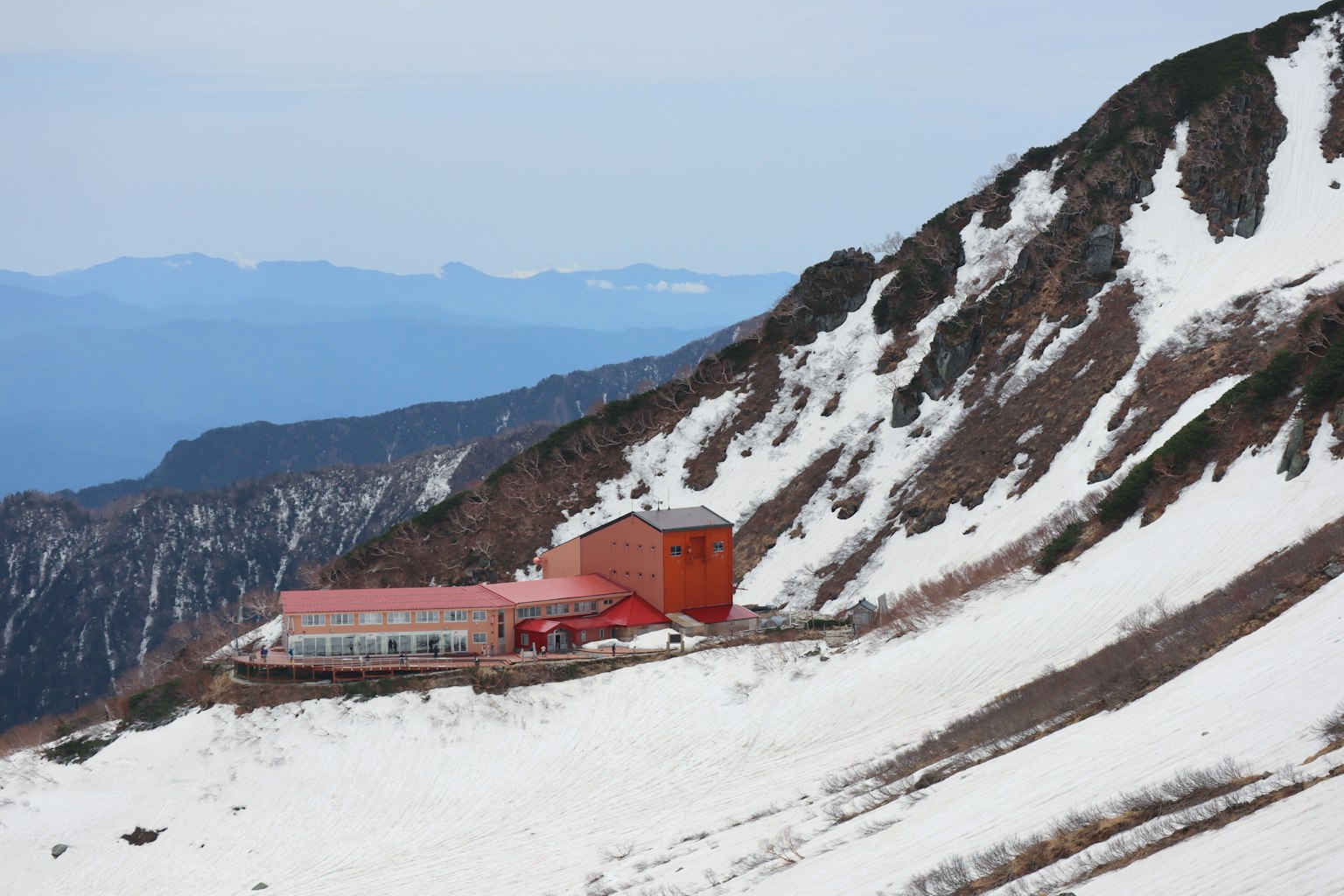 Edificio rosso su una pendenza montuosa innevata