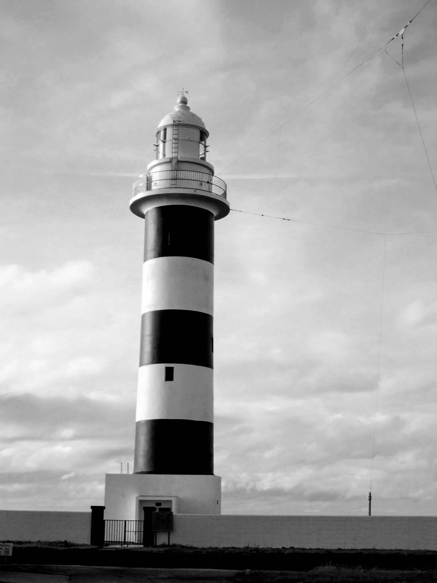 Faro a rayas blancas y negras de pie contra un cielo nublado