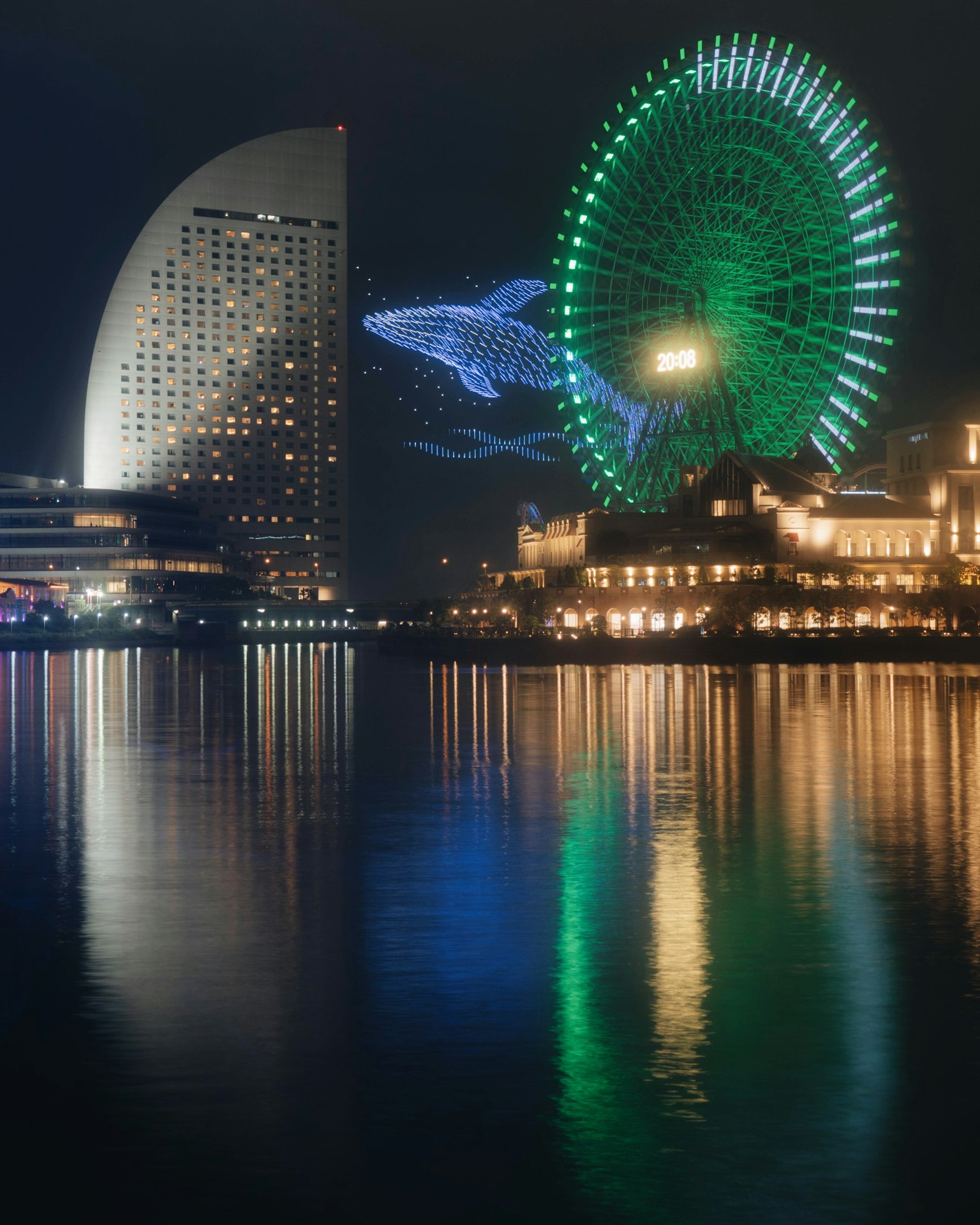 Pemandangan malam Yokohama dengan roda ferris hijau dan proyeksi ikan paus biru