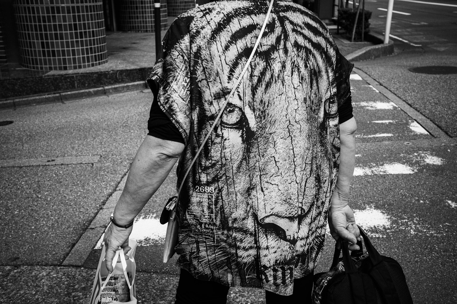 บุคคลที่สวมเสื้อยืดลายหน้เสือเดินอยู่บนถนน