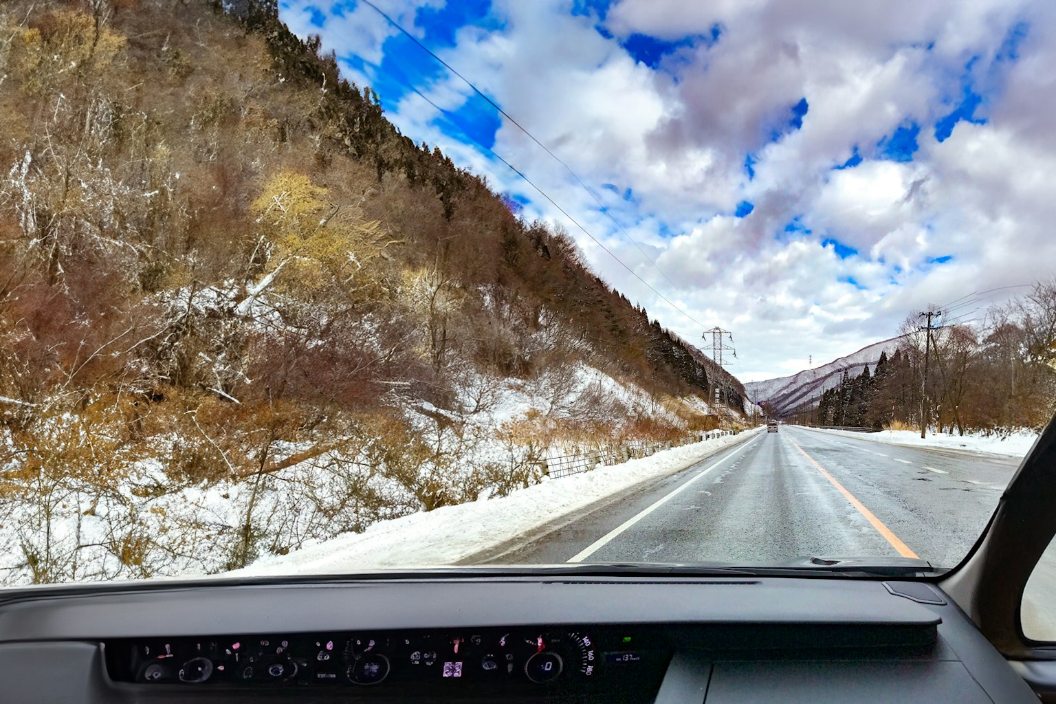 Camino cubierto de nieve con montañas y cielo azul