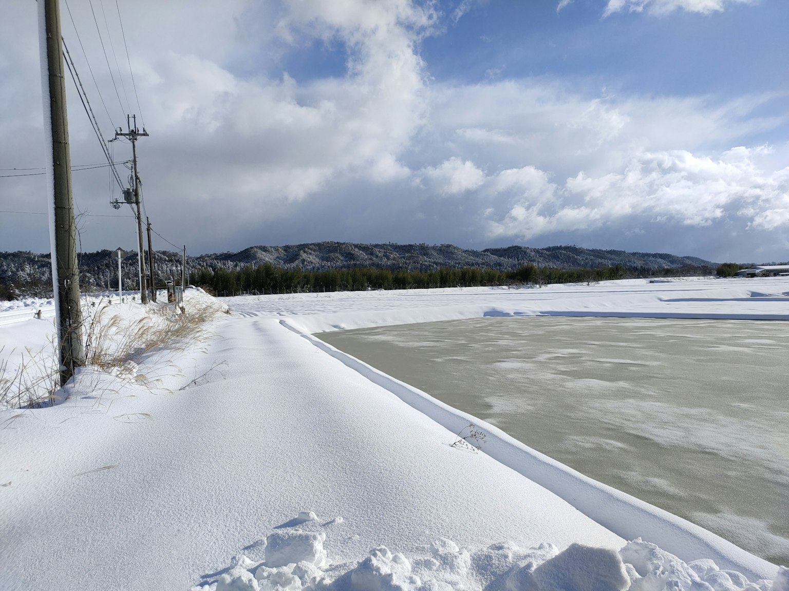 被雪覆盖的小路和冰冻水面，背景有山脉