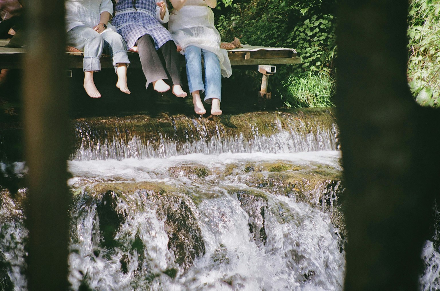 Foto dei piedi di persone che penzolano sopra una piccola cascata