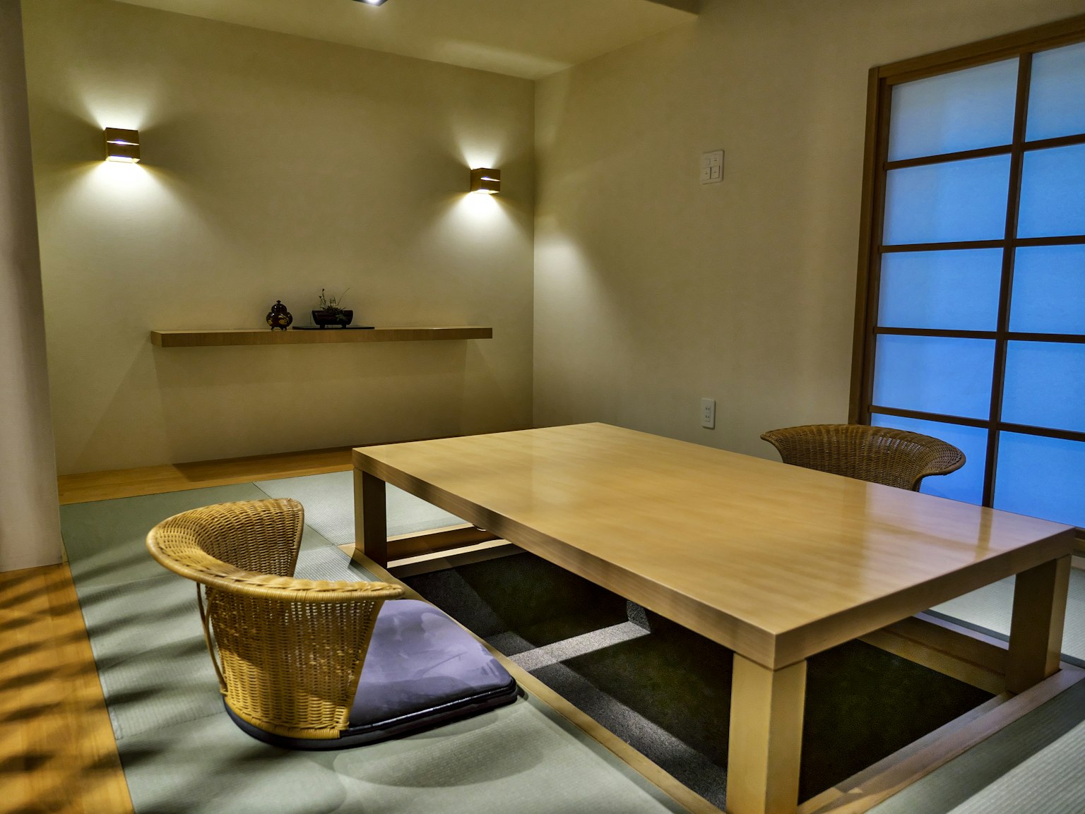 Ein minimalistischer japanischer Raum mit einem Holztisch und Rattanstühlen