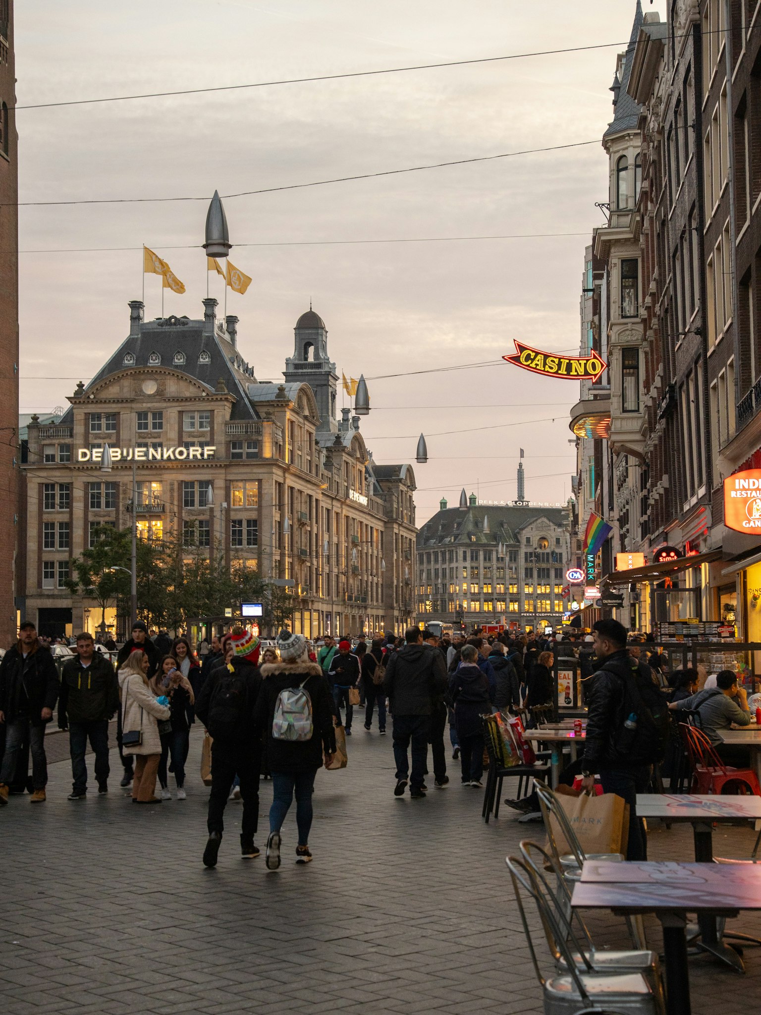 Strada affollata di Amsterdam al crepuscolo con persone e edifici storici