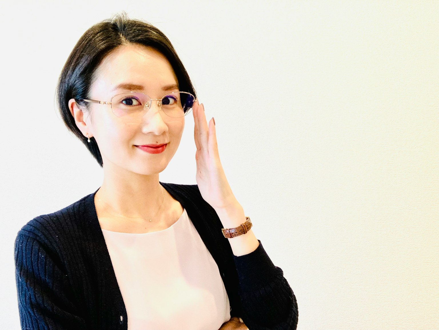 穿着黑色开衫的女性微笑着触碰眼镜