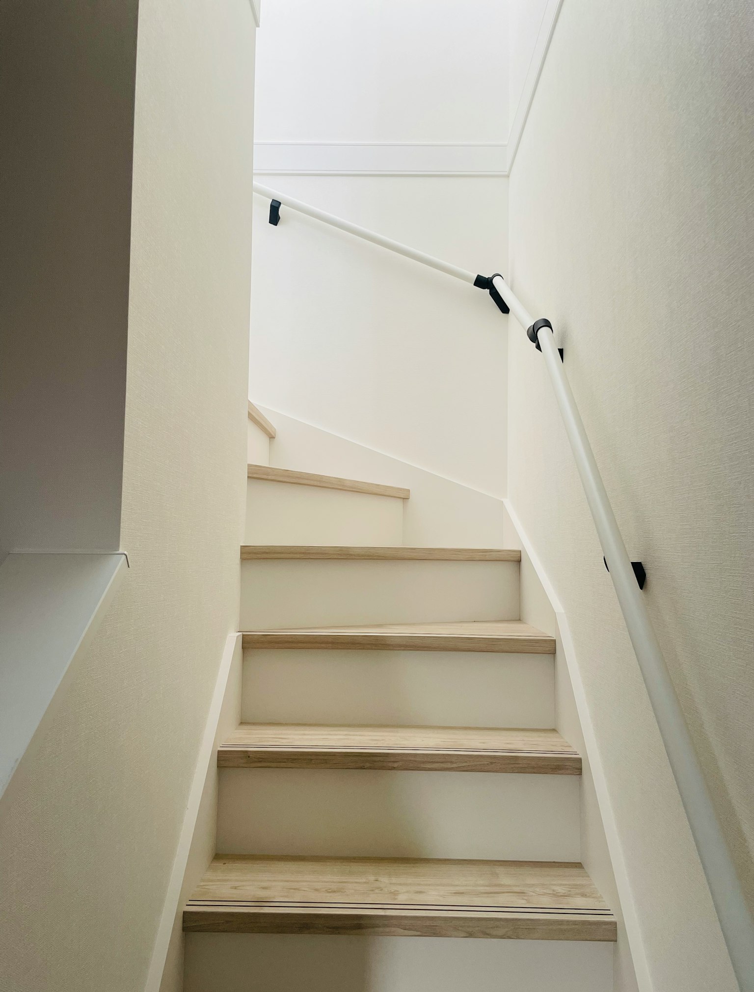 Escalera de madera que lleva hacia arriba rodeada de paredes blancas