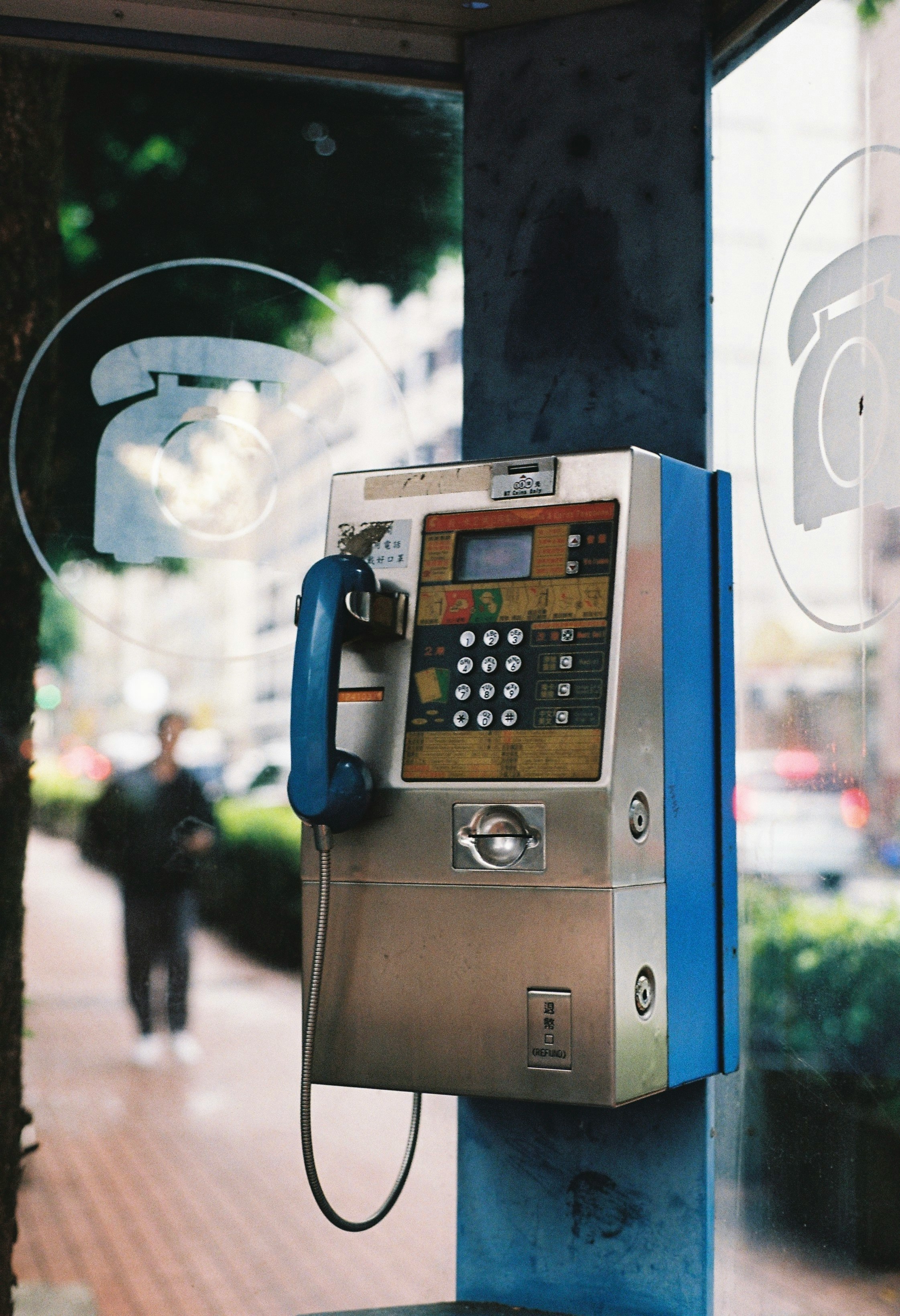public payphone booth on a city street with passersby