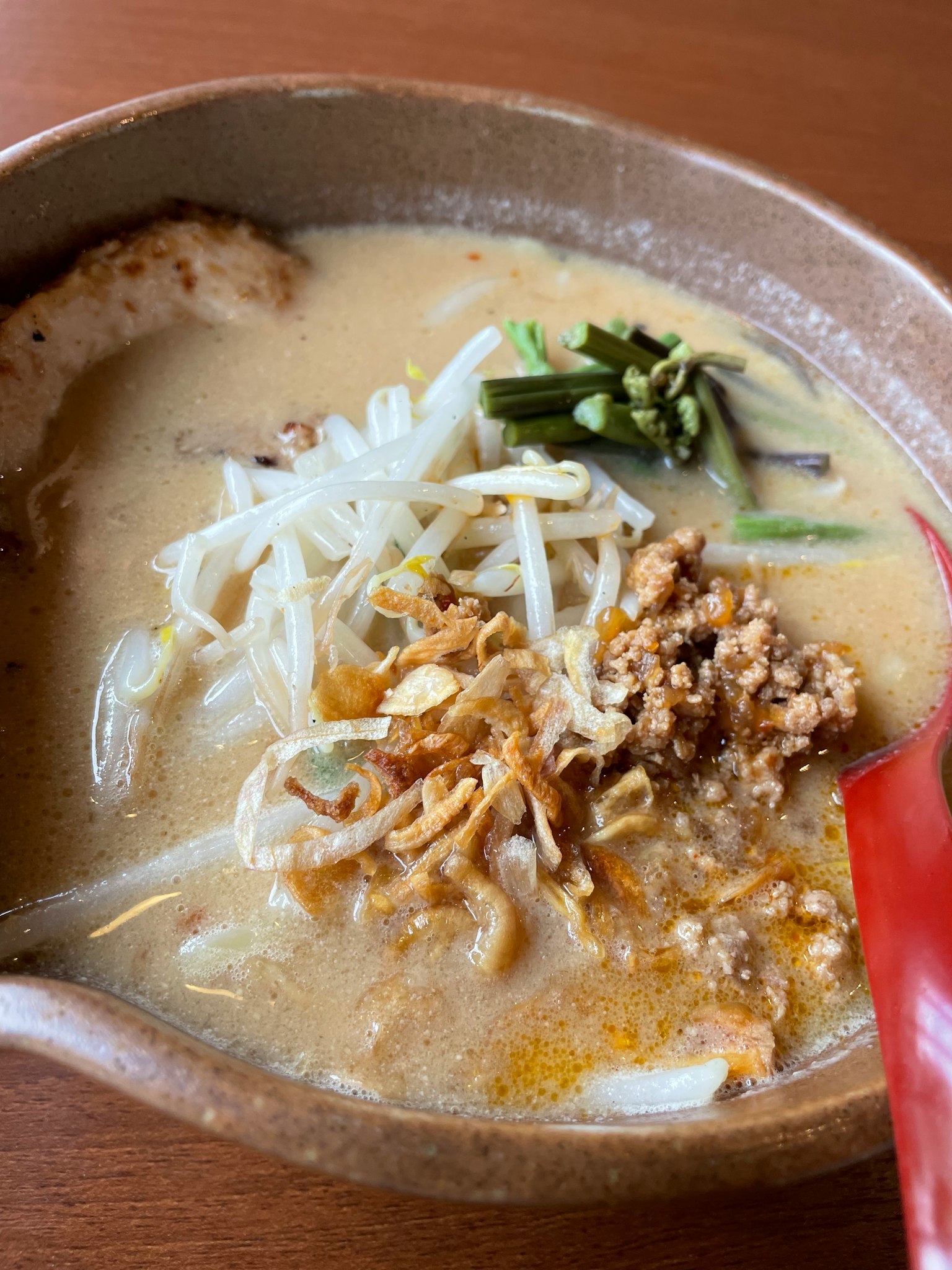 Bowl of ramen with pork slices and green onions topped with crispy garlic