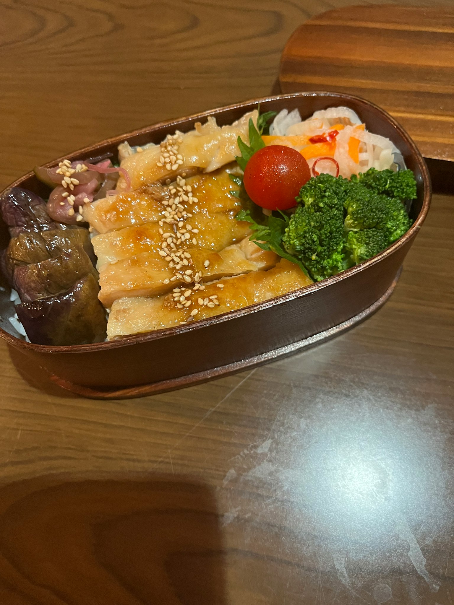 Bento avec poisson grillé et riz accompagné de brocoli et d'une tomate cerise