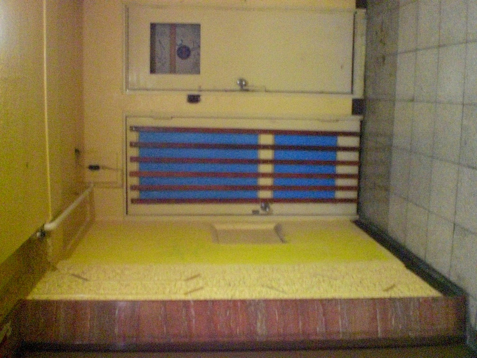 Interior de una habitación con paredes amarillas y una ventana azul