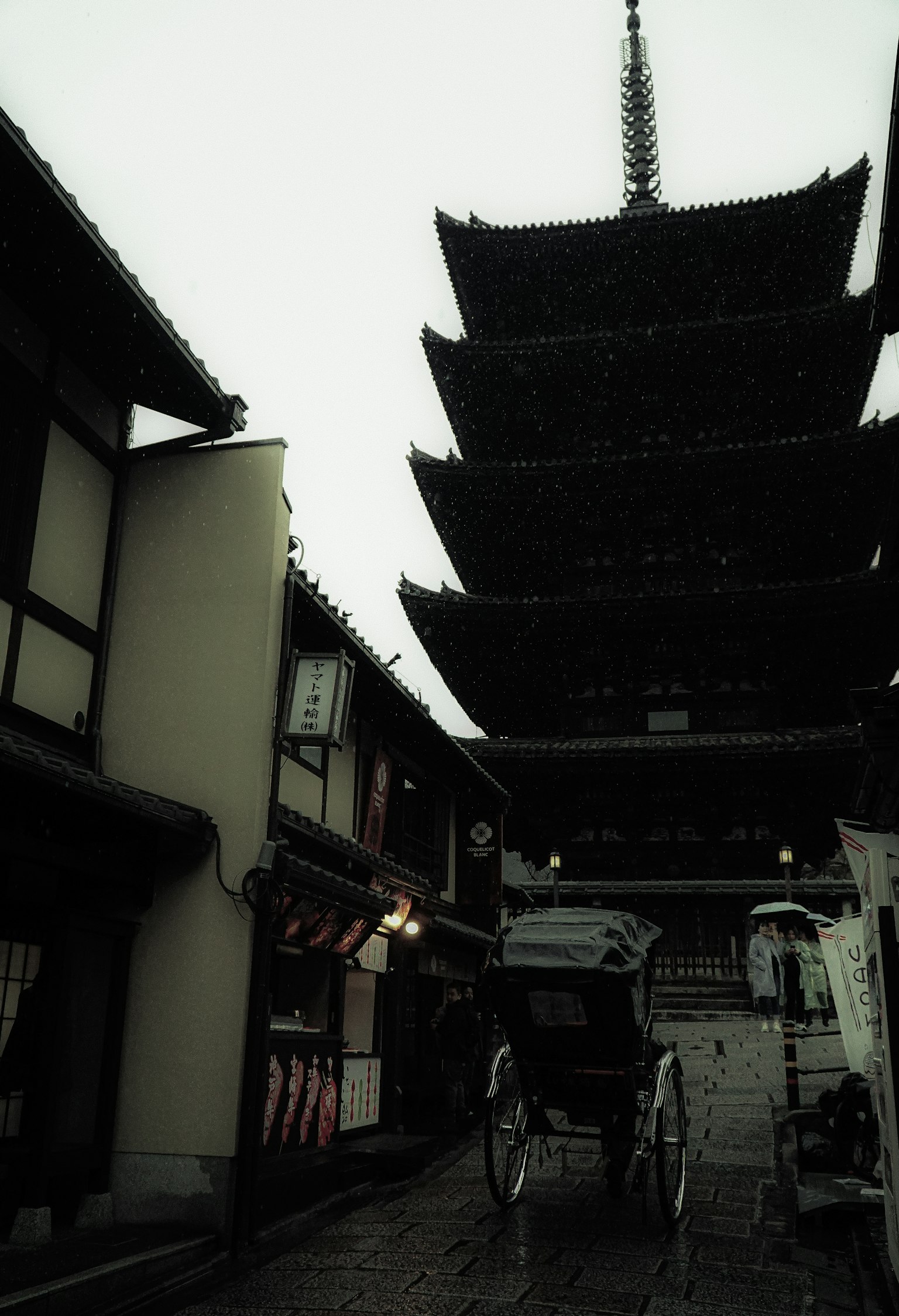 Rue historique avec une pagode et un pousse-pousse sous la pluie
