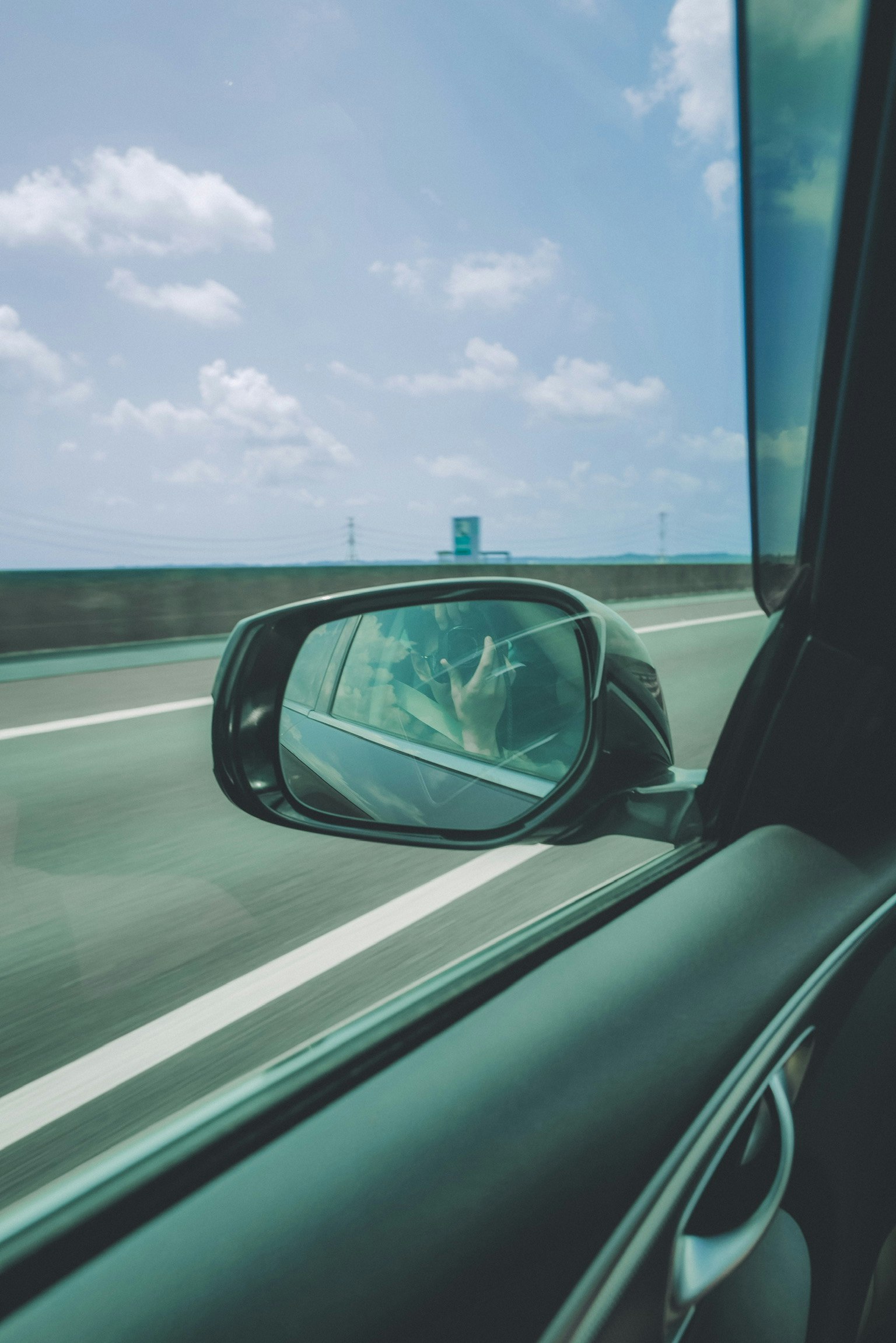 Vista da un finestrino dell'auto che mostra la strada e il riflesso del cielo blu