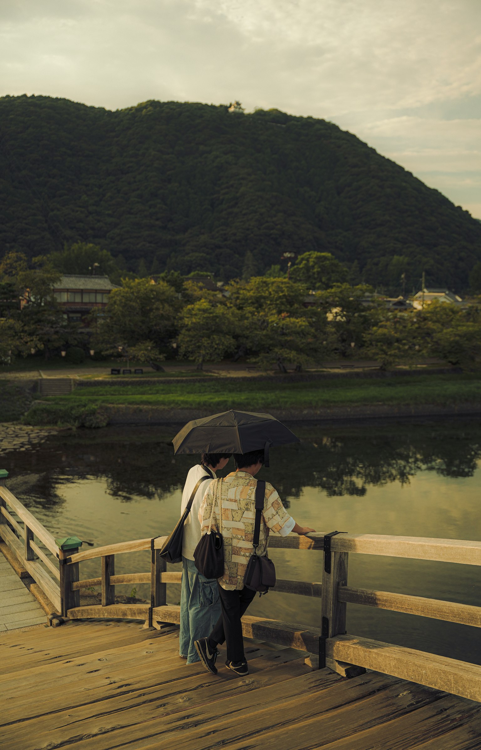 山の背景に立つカップルが傘を持っている