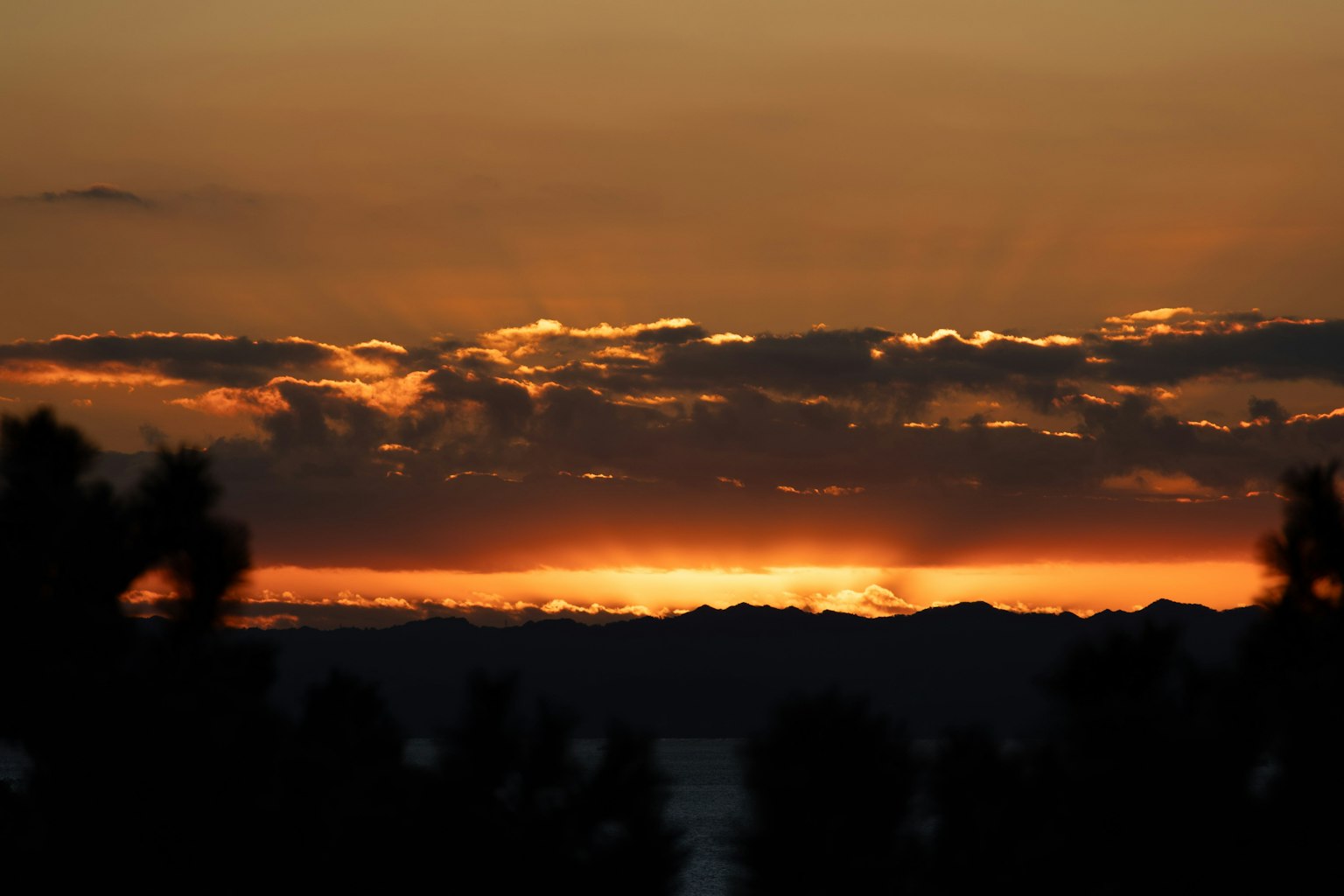 Bellissimo paesaggio al tramonto con silhouette di montagne e cielo arancione viola