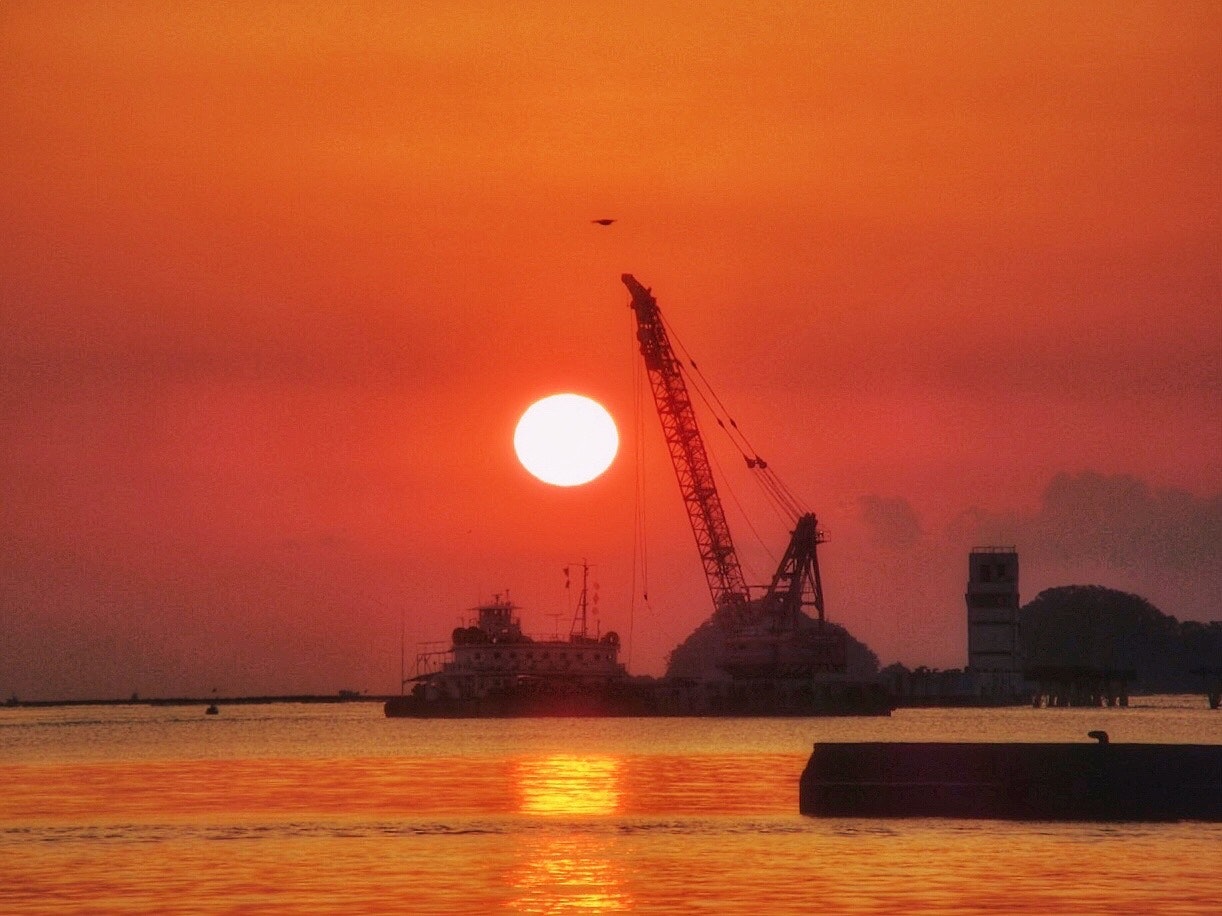 海上の重機と朝陽の朝焼けの風景